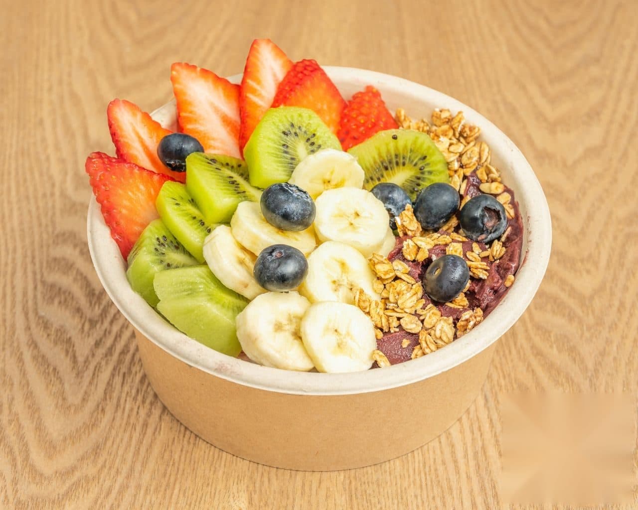 Açaí bowl con granola, fresas y kiwi servido en bol kraft